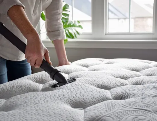 person vacuuming their white mattress